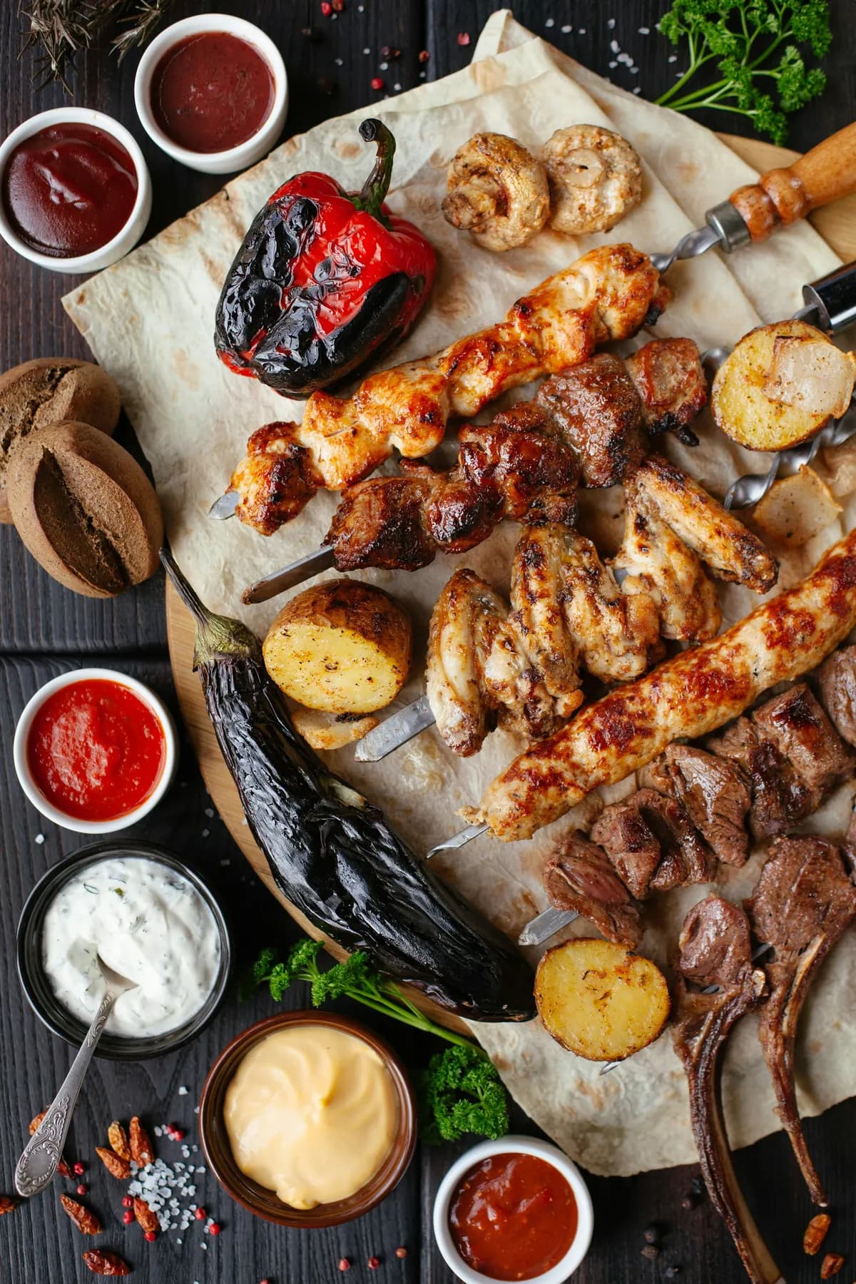 Gegrillte Spieße, Paprika und Fladenbrot auf einem Holzbrett