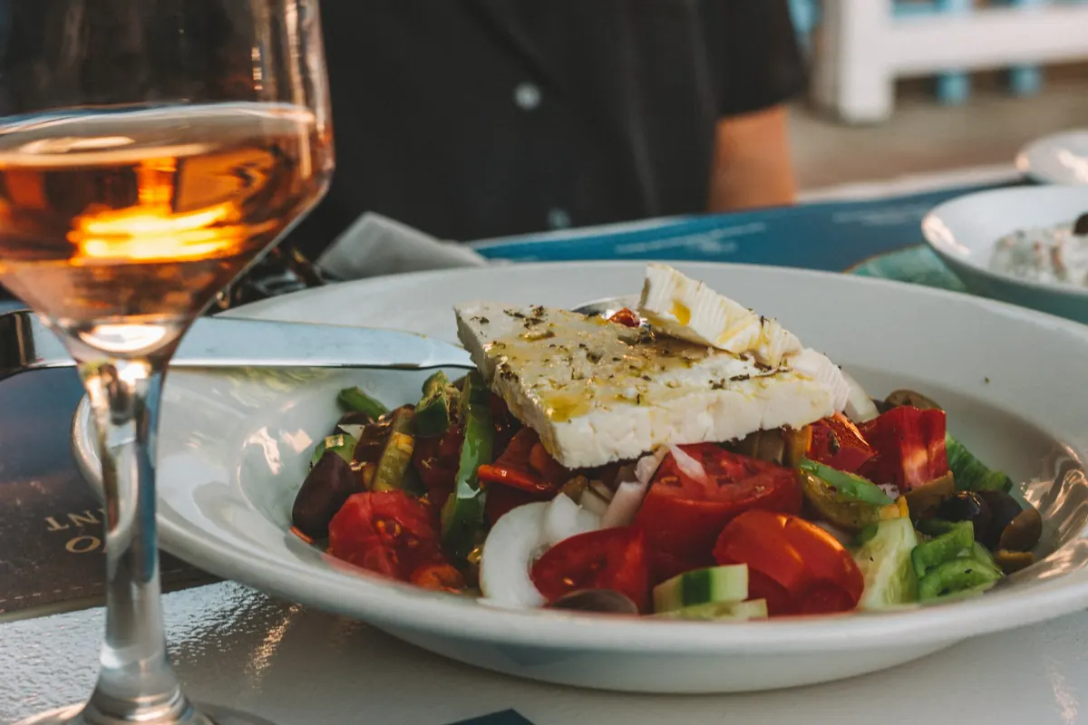 Griechischer Salat mit Feta neben einem Glas Roséwein